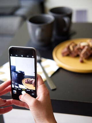 Una persona scatta una foto al proprio piatto, utilizzabile dal ristorante per fare pubblicità gratis alla propria pagina facebook